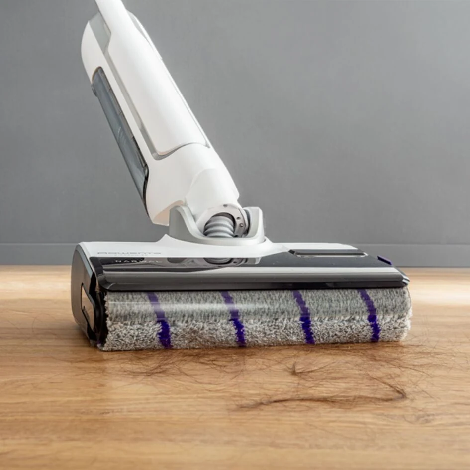 Tête du Rowenta X-Clean 10 et rouleau gris à bandes violettes, photographiés sur un sol en bois.