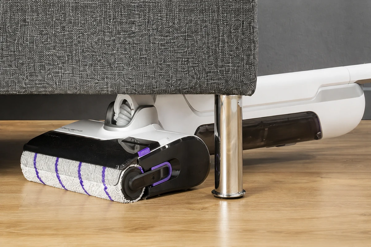 Rowenta X-Clean 10 incliné à plat sous un canapé. Photo de référence nettoyée avec l’IA.